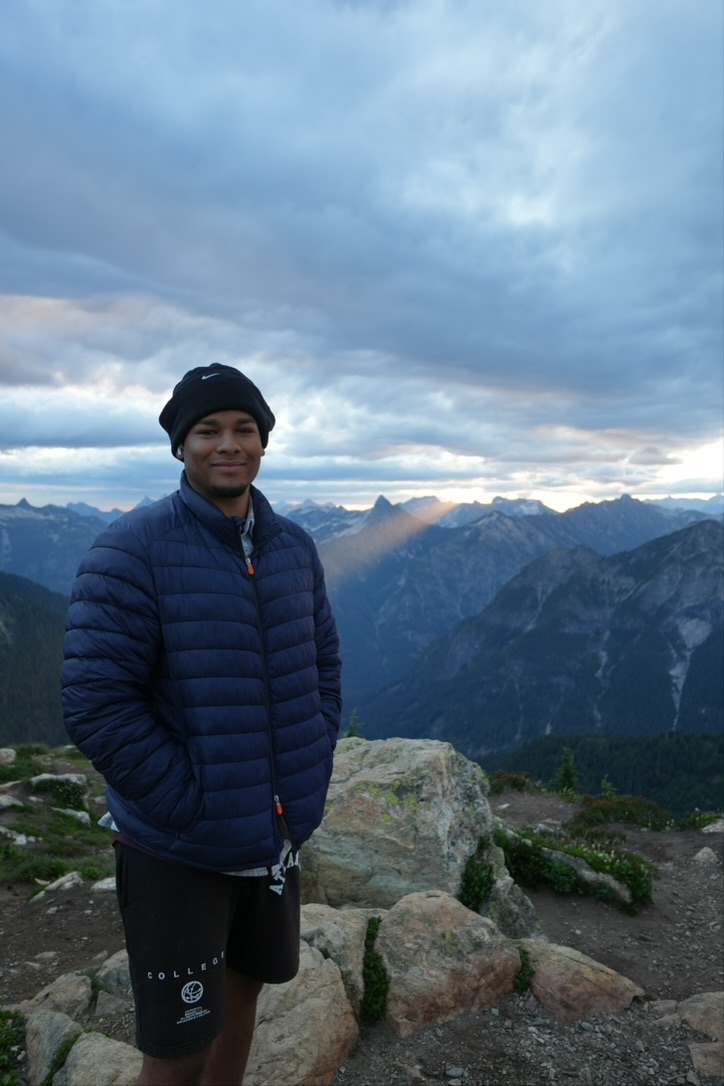 Shawn standing above a mountain range at sunset